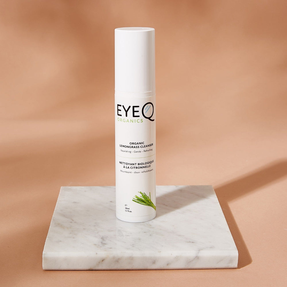 EQO Organic Lemongrass Cleanser placed on solid surfacing with a contrasting coral background. The bottle highlights one of the primary Ingredient, Lemongrass, paired with Kakadu Plum Seed Oil.