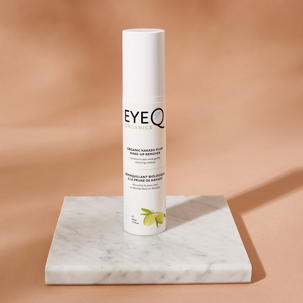 EyeQ Organics makeup remover bottle on a marble surface with a beige background. The bottle highlights one of the primary Ingredient, Kakadu Plum Seed Oil, paired Shea Nut Butter, Rosehip Seed Oil,  and Potassium Coconate.